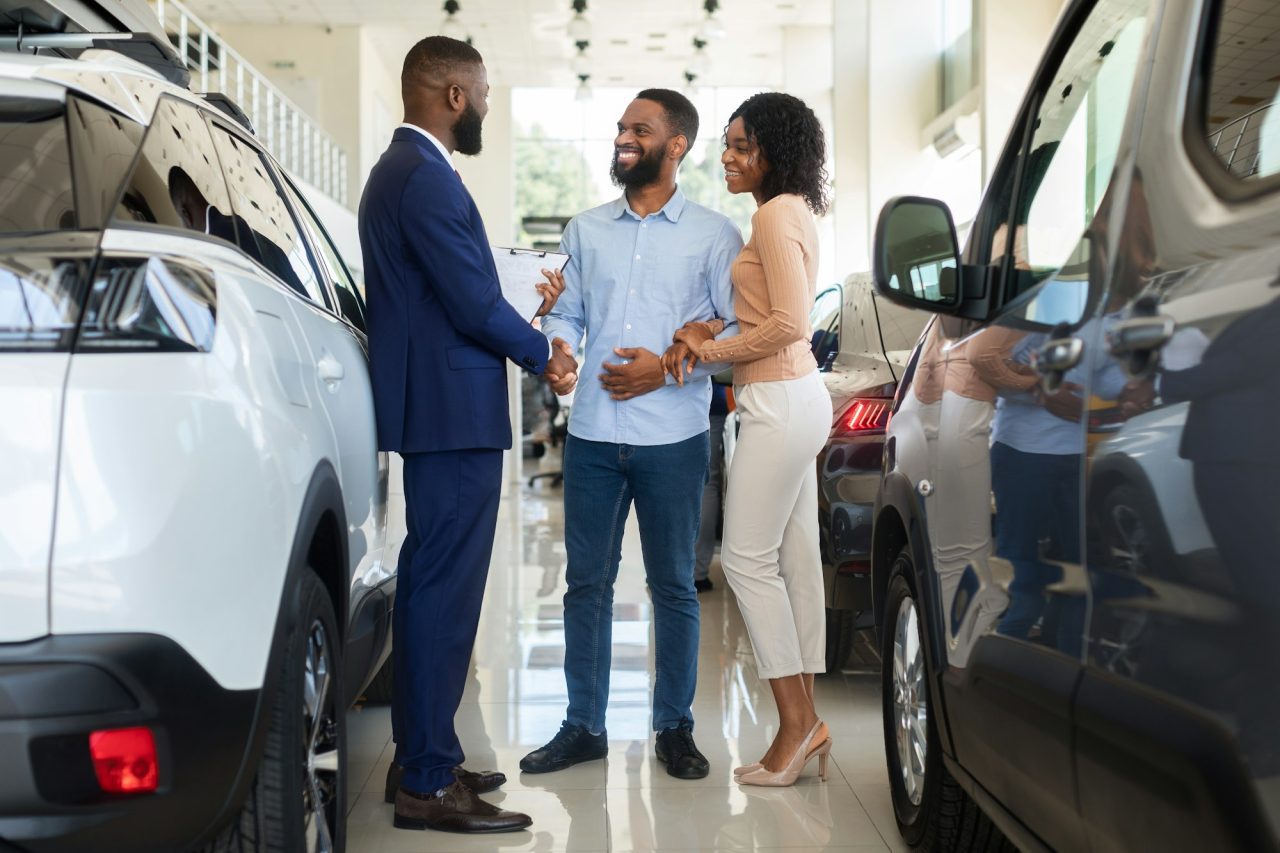 car-purchase-happy-customers-couple-handshaking-with-manager-in-auto-salon.jpg