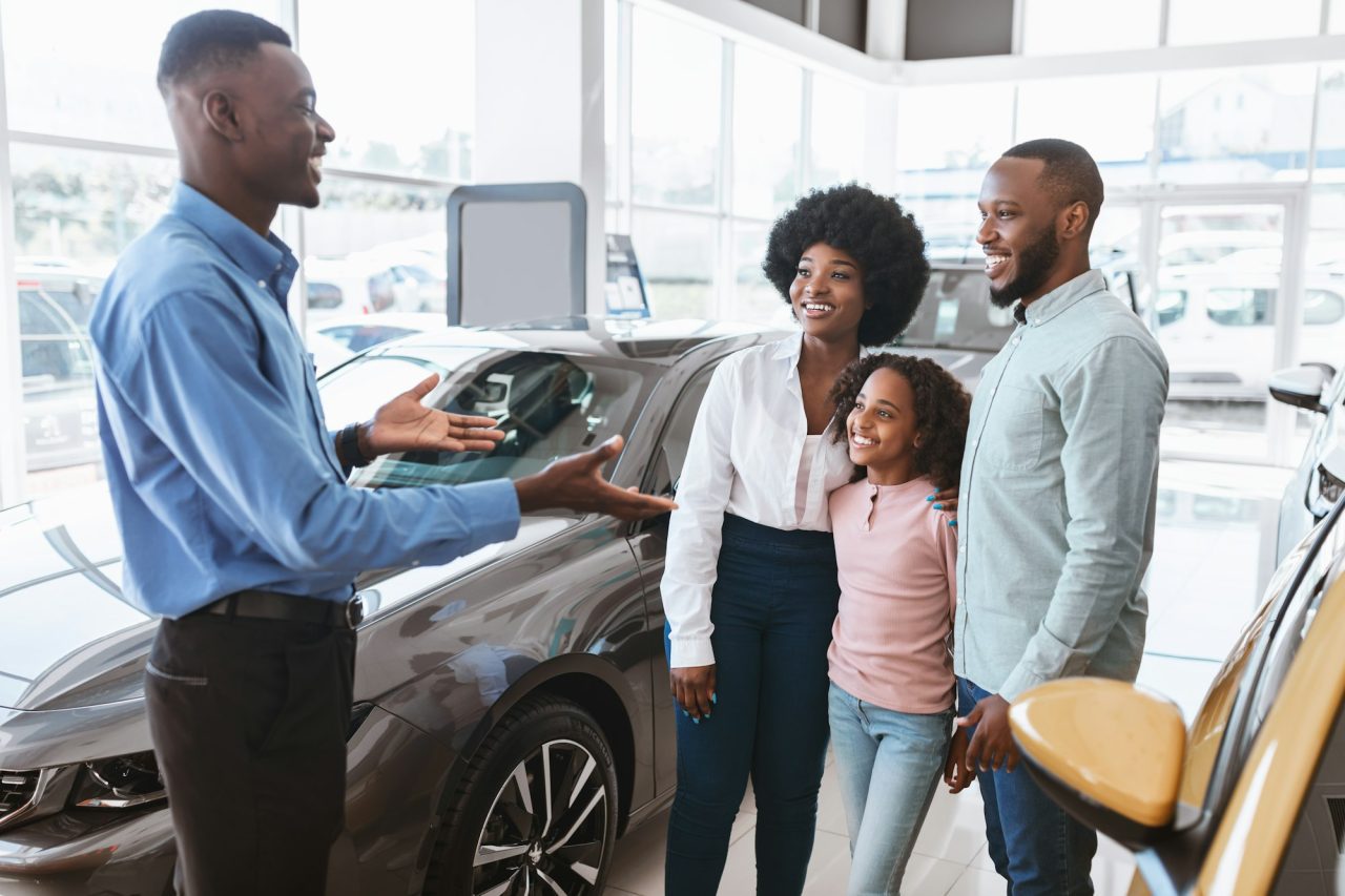 car-purchase-or-rental-millennial-black-family-with-kid-speaking-to-salesman.
